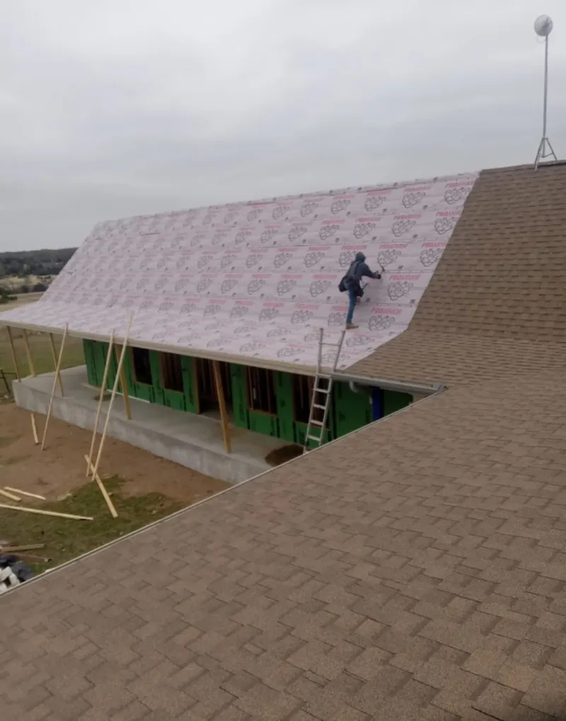 Worker preparing underlayment for a metal roof installation in Racine